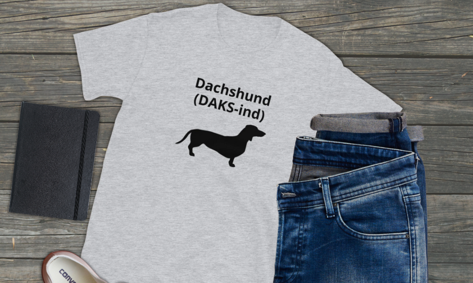Whit dachshund t-shirt with black dachshund outline with phonetic pronunciation of how to say dachshund