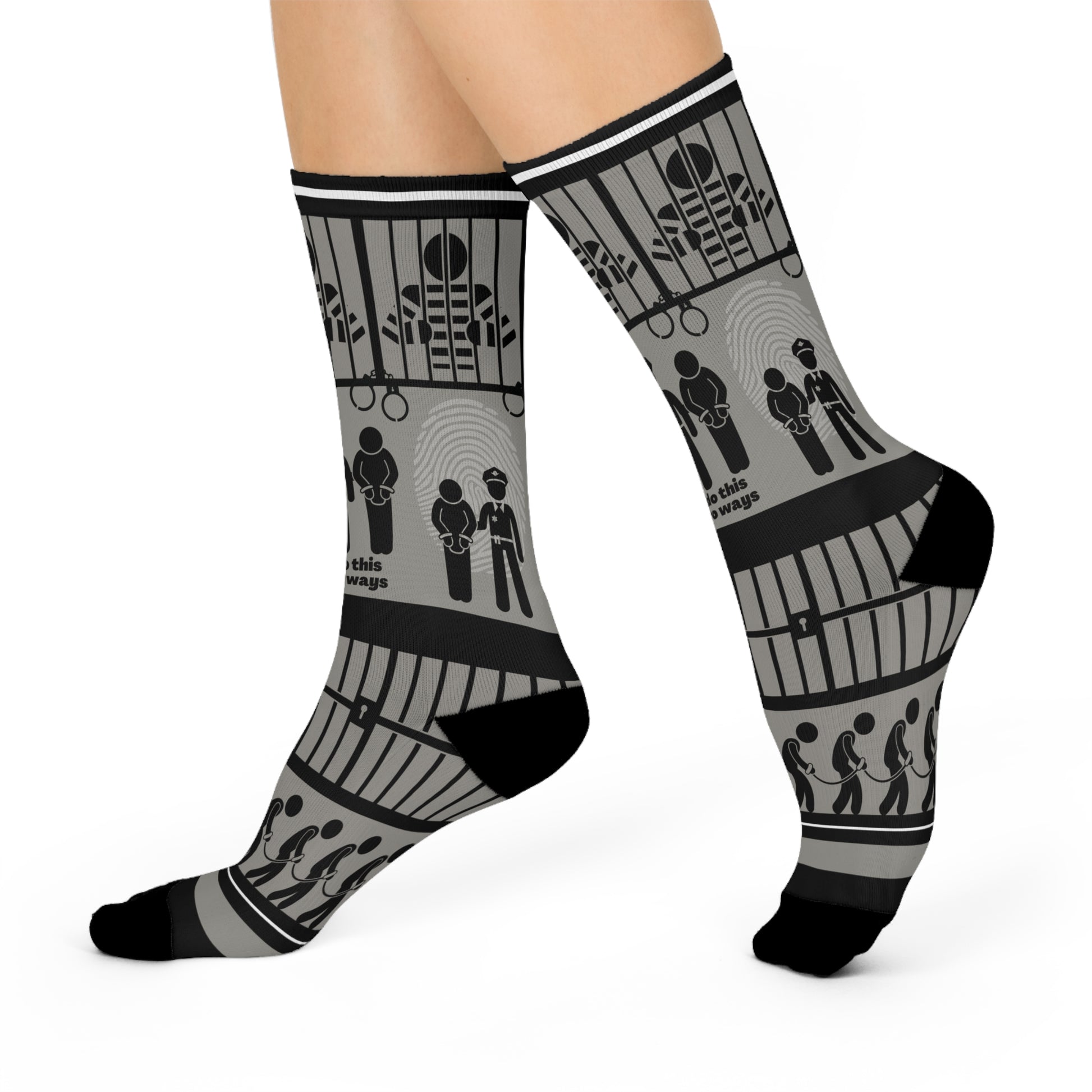 A pair of black and white crew socks with a geometric pattern, featuring designs that include cubes and what appears to be a representation of a police station or jail.