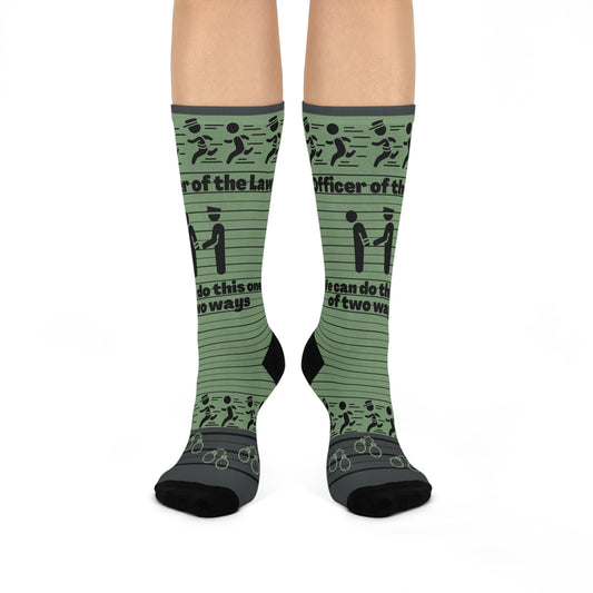 A pair of green crew socks with text and graphic patterns related to law enforcement, including phrases such as 'Law and Order' and 'Officer of the People'.